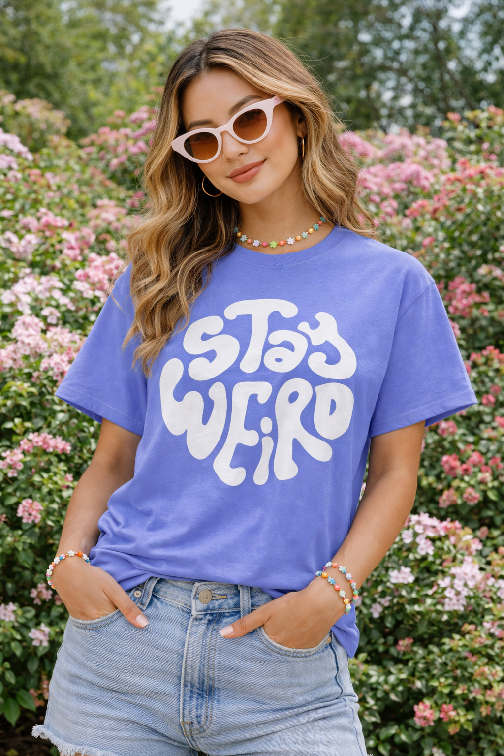 Woman wearing a purple t-shirt with 'Stay Weird' text in a garden setting