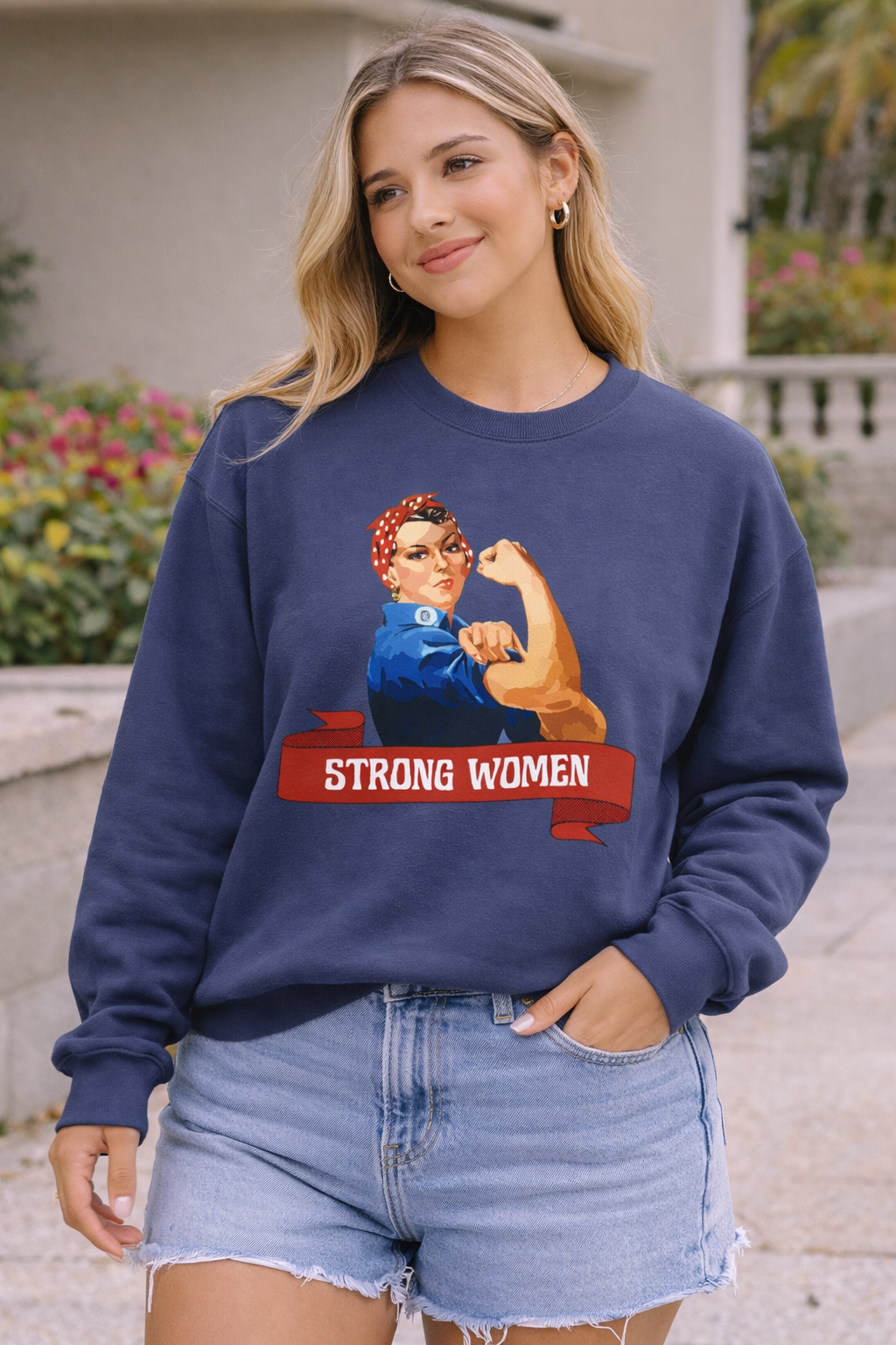 Woman wearing a navy blue sweatshirt with a graphic of a strong woman and text 'STRONG WOMEN'.