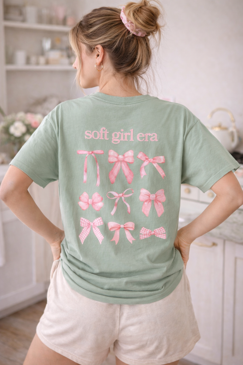 Person wearing a green t-shirt with pink graphics and text in a kitchen setting