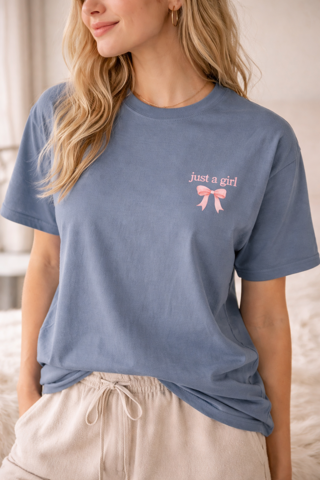 Woman wearing a blue t-shirt with 'just a girl' and a pink bow graphic.