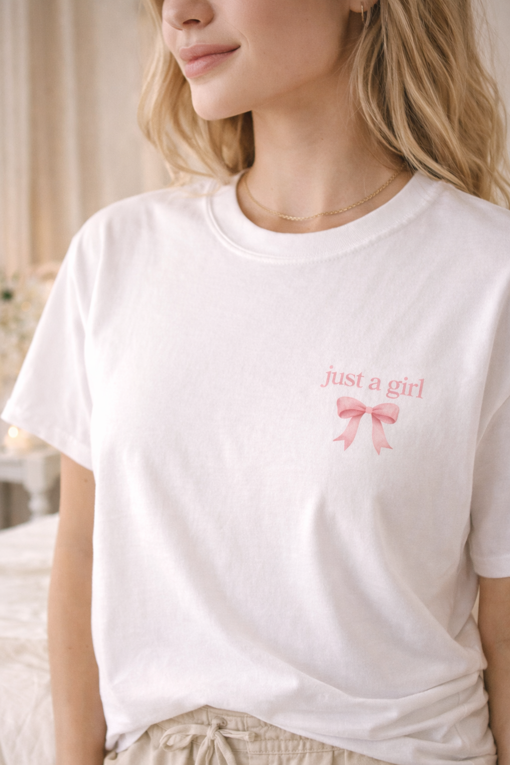 Woman wearing a white t-shirt with 'just a girl' and a pink bow design.