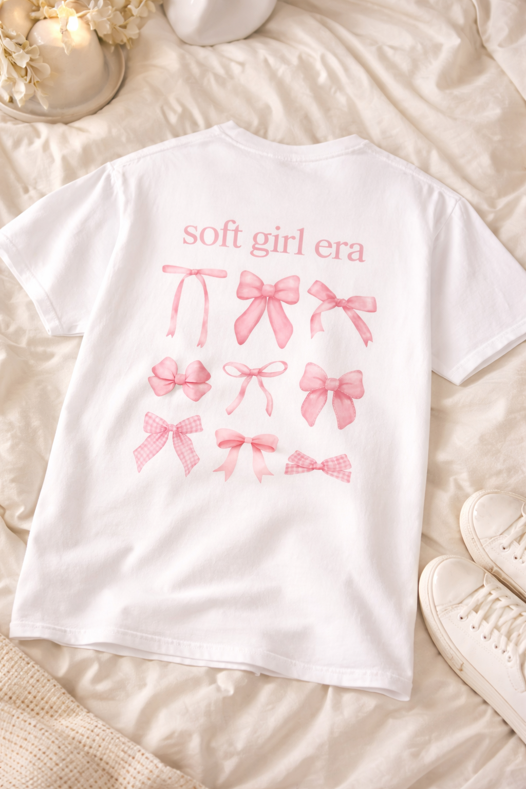 White t-shirt with pink graphics and text on a soft, beige surface