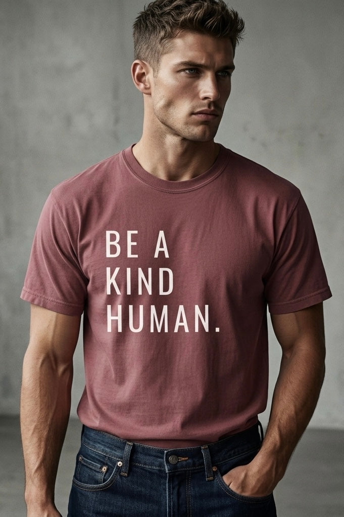 Man wearing a t-shirt with 'BE A KIND HUMAN.' text against a gray background
