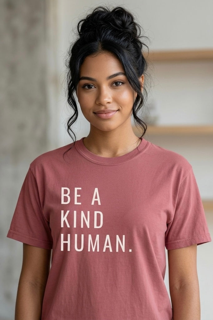 Person wearing a pink t-shirt with 'Be a Kind Human' text.