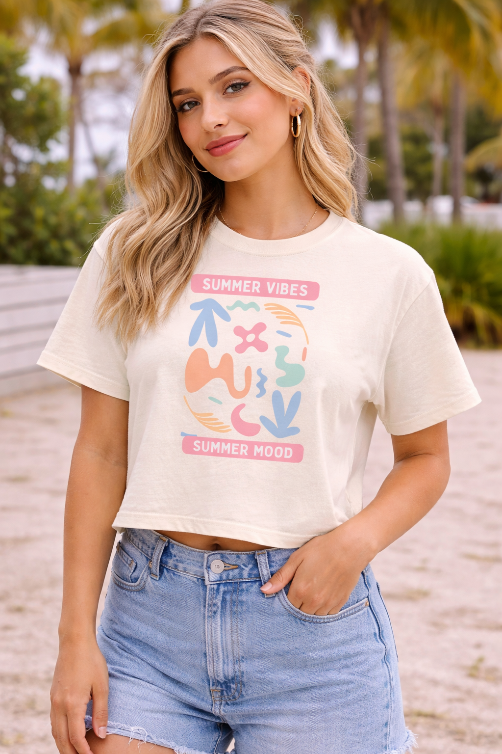 Woman wearing a white t-shirt with colorful text and graphics on a beach.