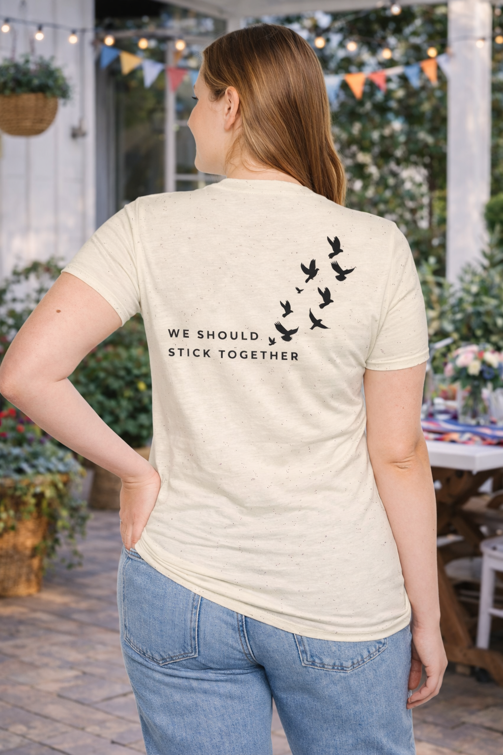 Person wearing a t-shirt with 'We Should Stick Together' text and bird design on the back, standing outdoors.