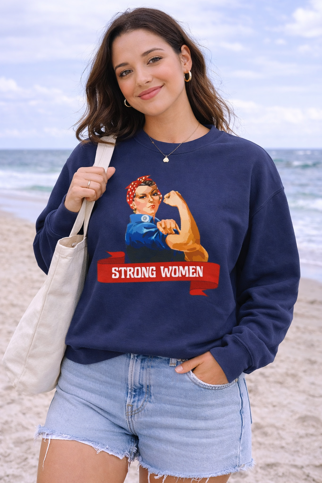 Woman wearing a navy sweatshirt with a 'Strong Women' graphic on a beach