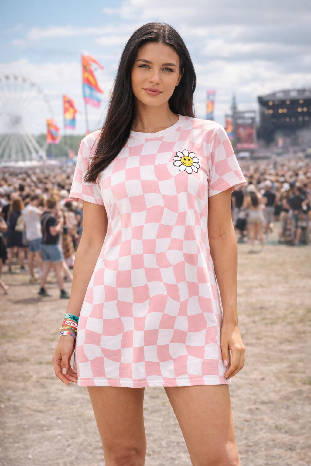 Woman wearing a pink checkered dress with a smiley flower design at a music festival.
