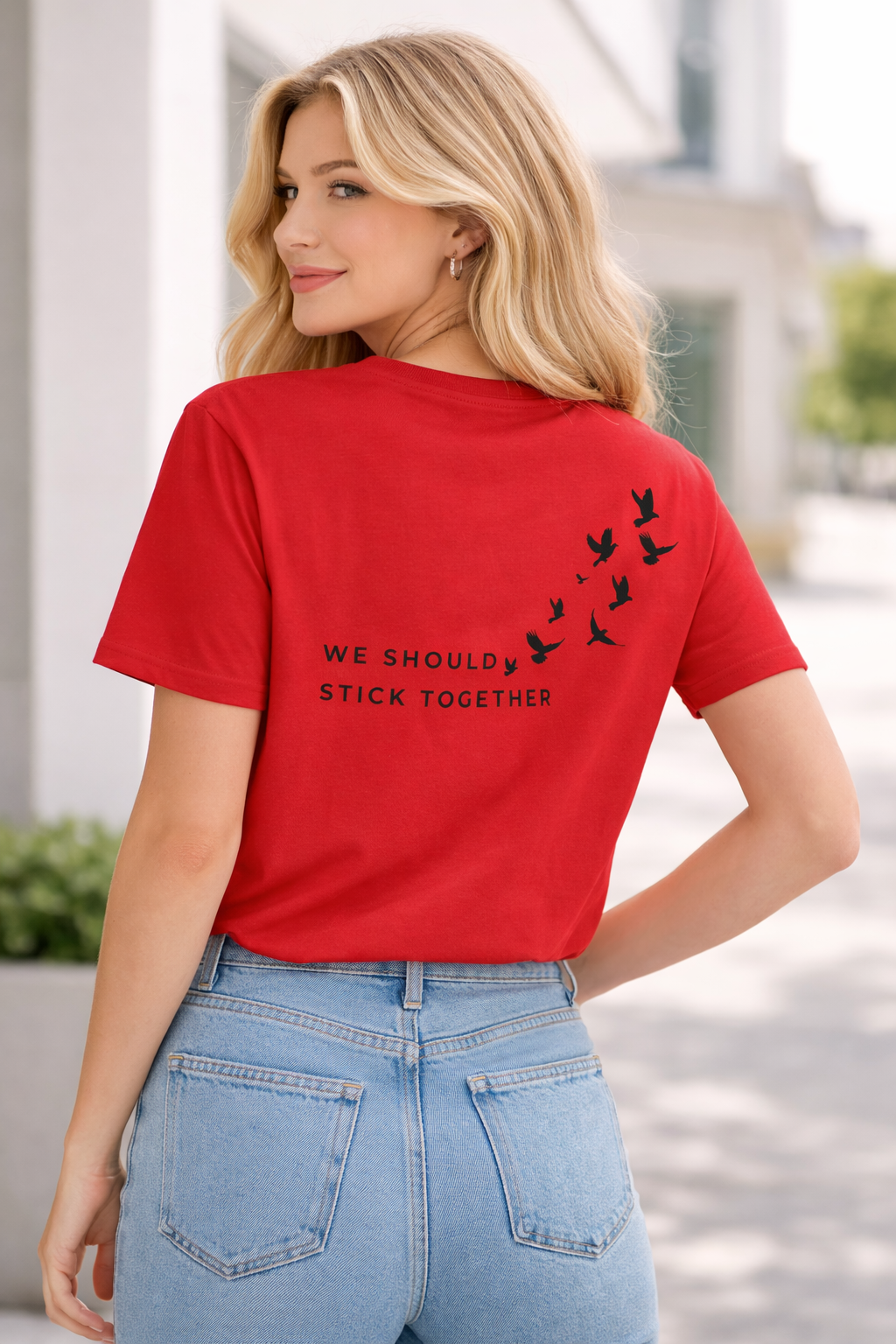 Woman wearing a red t-shirt with text and bird graphics outdoors