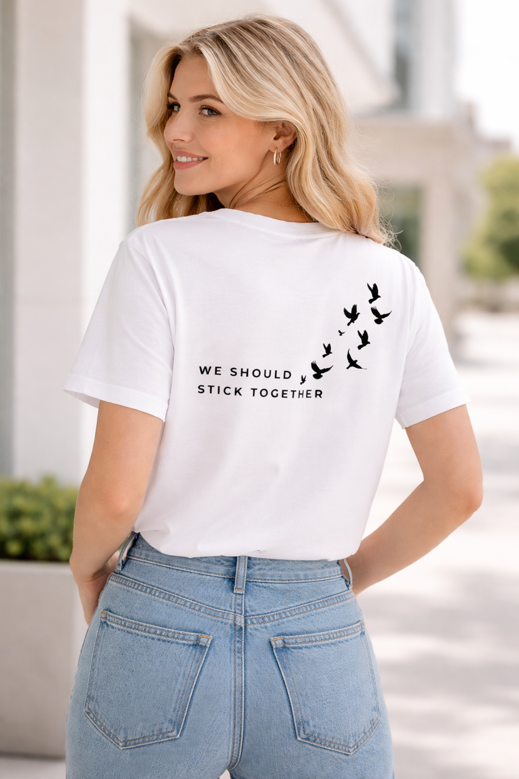 Woman wearing a white t-shirt with text and bird graphics outdoors