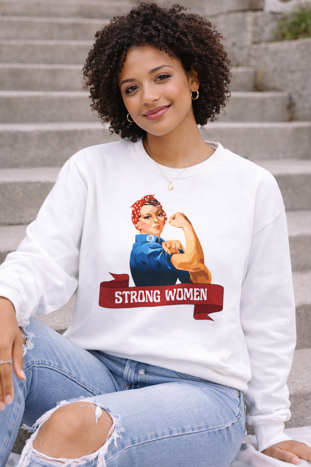 Person wearing a white sweatshirt with a graphic of a woman flexing her arm and the text 'Strong Women'.
